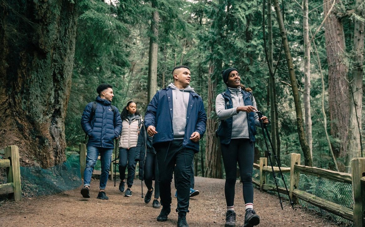 Skupina turistů v trekových botách na lesní cestě